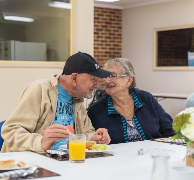 Elderly couple enjoying breakfast and chat at a table