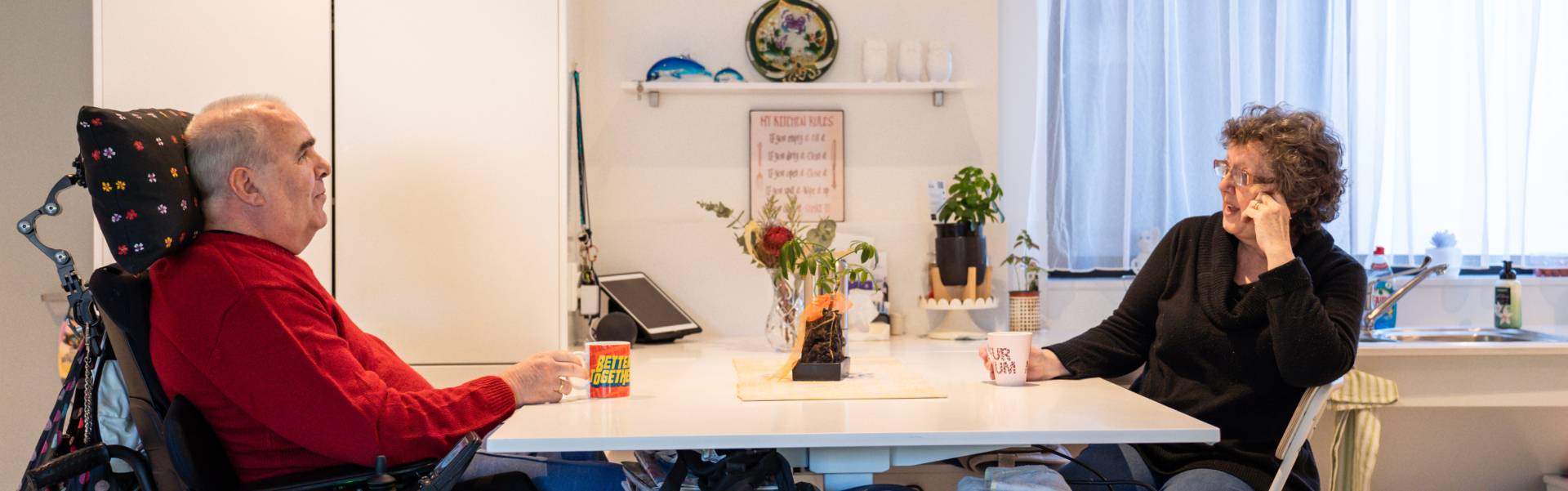 Disabled man and woman chatting at the kitchen table