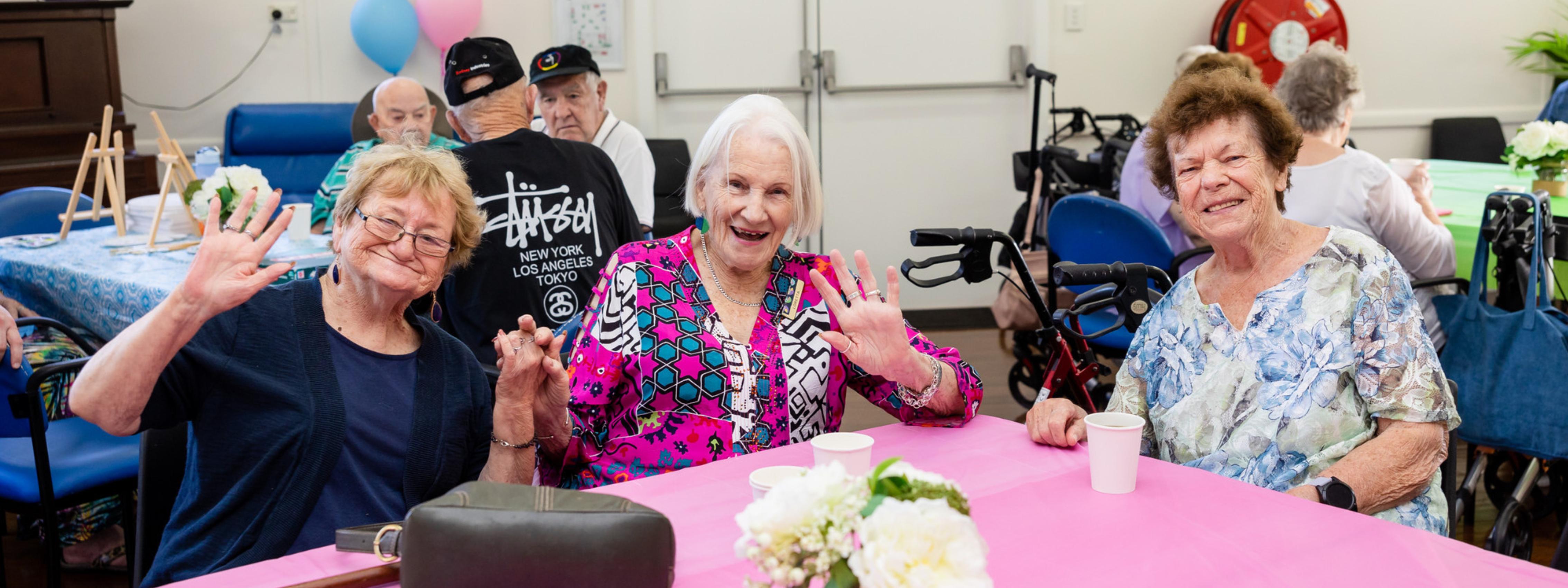 Three older ladies wave at the camera